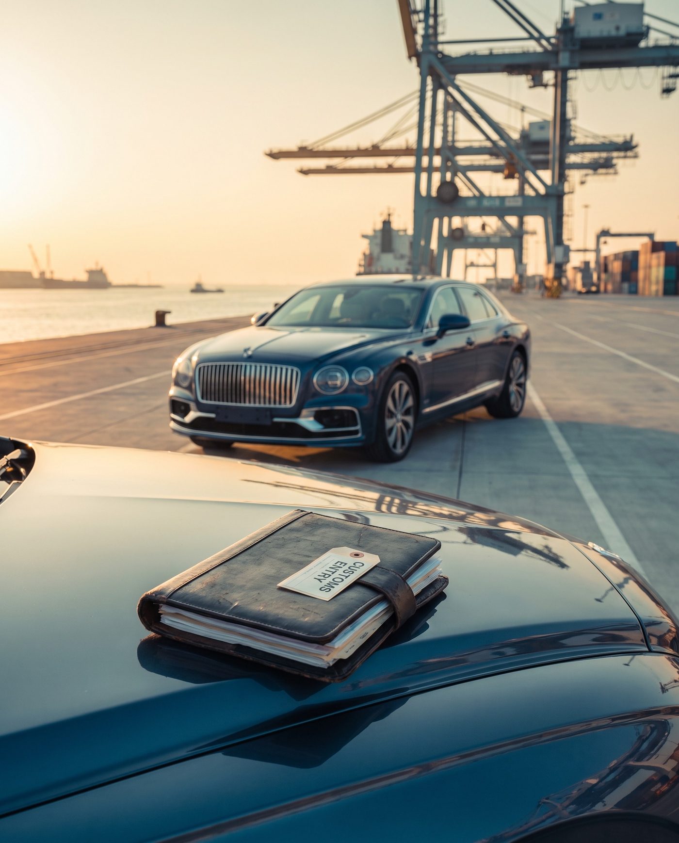 Bentley Flying Spur at a destination port with a customs entry document folder on the hood